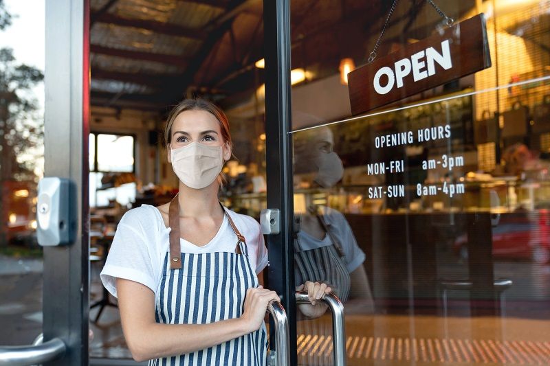 Happy-business-owner-opening-the-door-at-a-cafe-wearing-a-facemask-cm