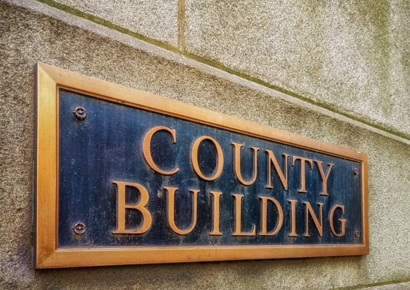 Exterior sign that reads County Building in brass letters.-cm